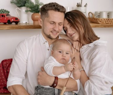 A joyful family of three embracing in a cozy kitchen. Warm and loving atmosphere.